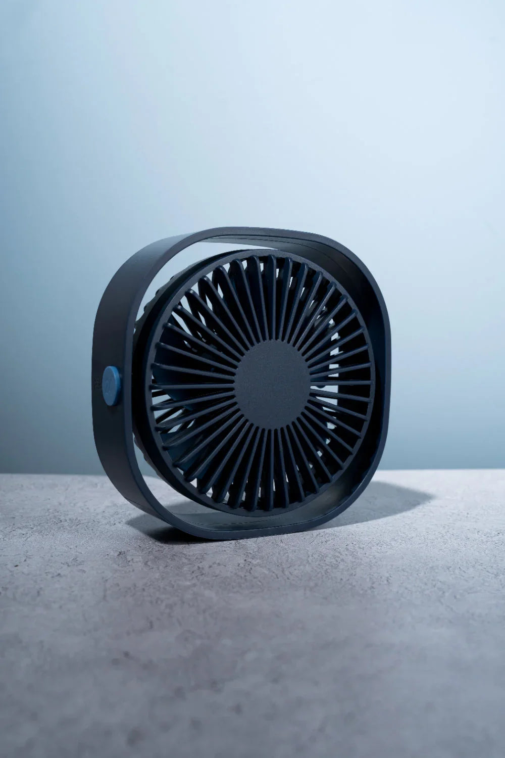 Ventilador de pie moderno con altura ajustable y cabezal oscilante en sala iluminada.