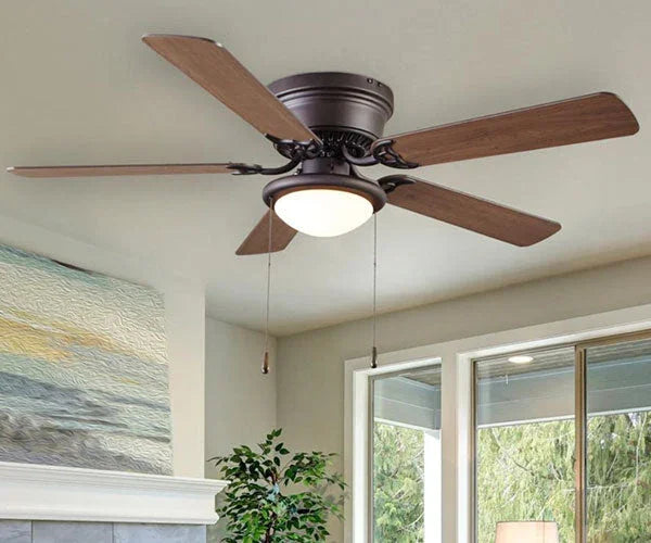 Ventilador de techo moderno instalado en un salón, con diseño elegante y aspas de madera natural.